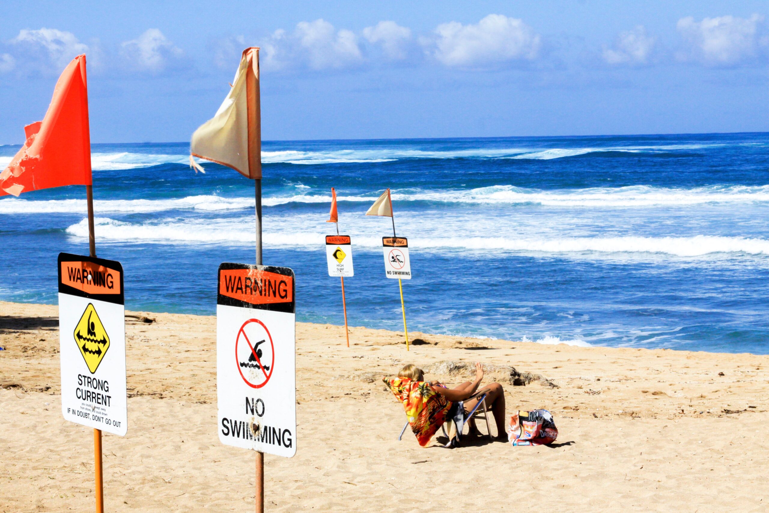 Plage très ensoleillée avec panneau d’avertissement et océan