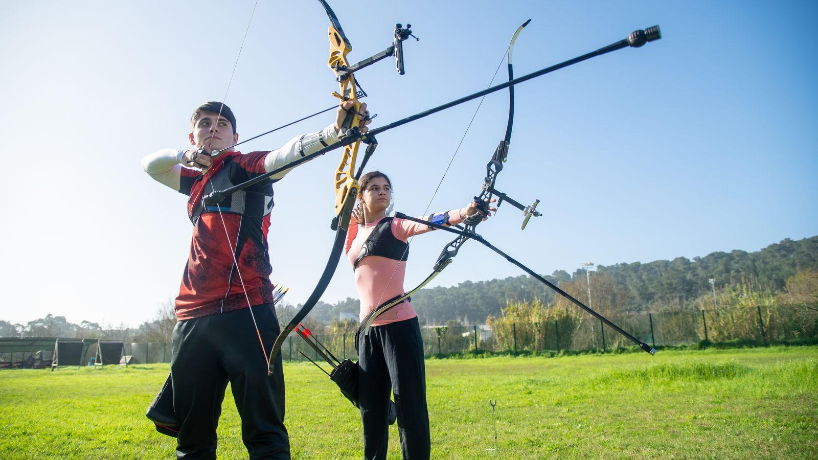 Deux archers visant une cible avec des arcs différents en extérieur