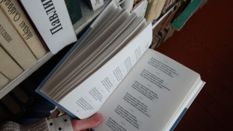 Lecteur tenant un livre devant une bibliothèque