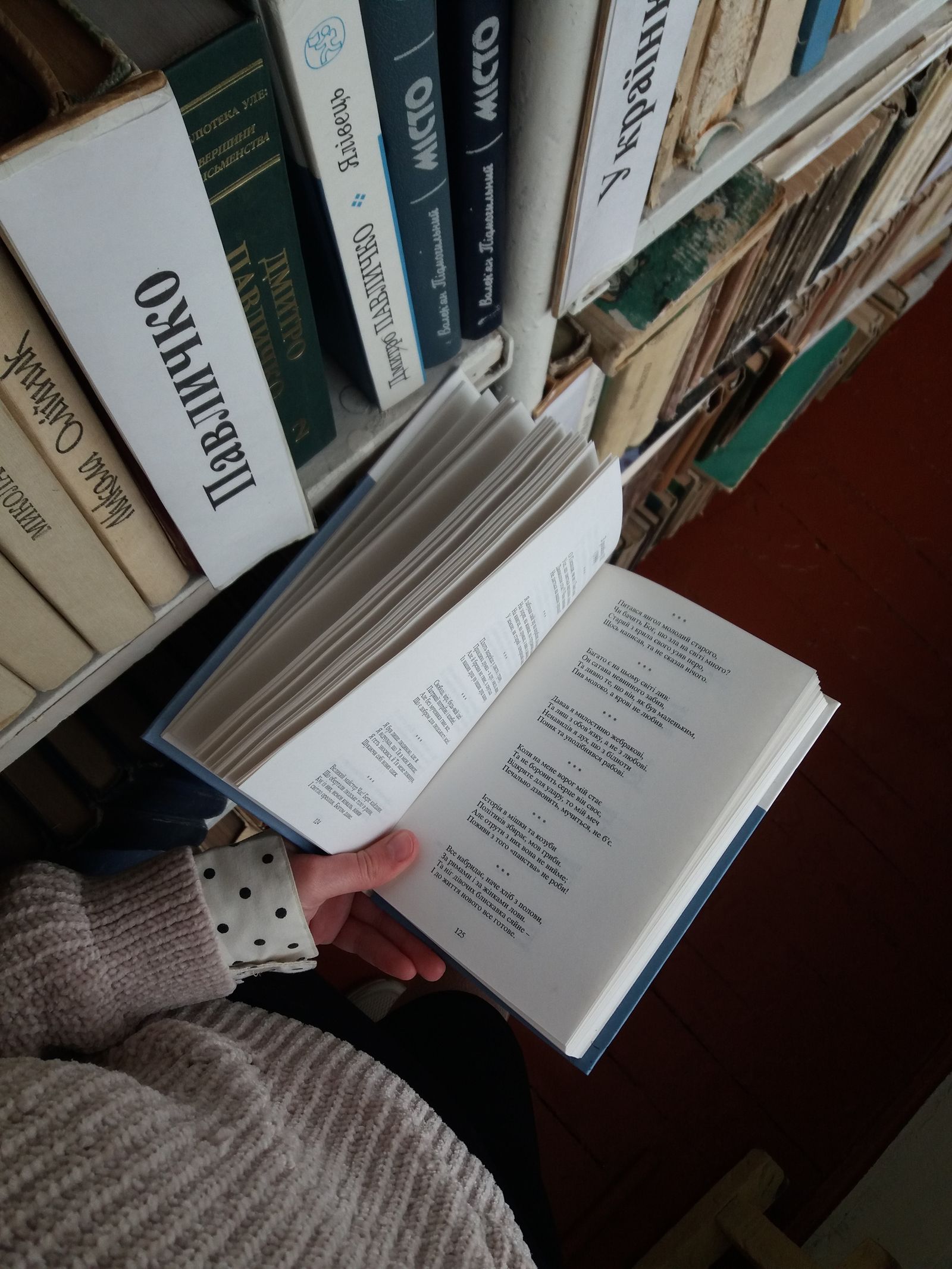 Lecteur tenant un livre devant une bibliothèque