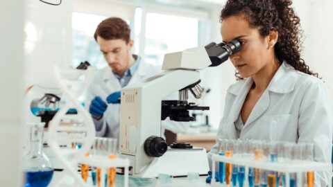 Une professionnelle observe un échantillon au microscope dans un laboratoire