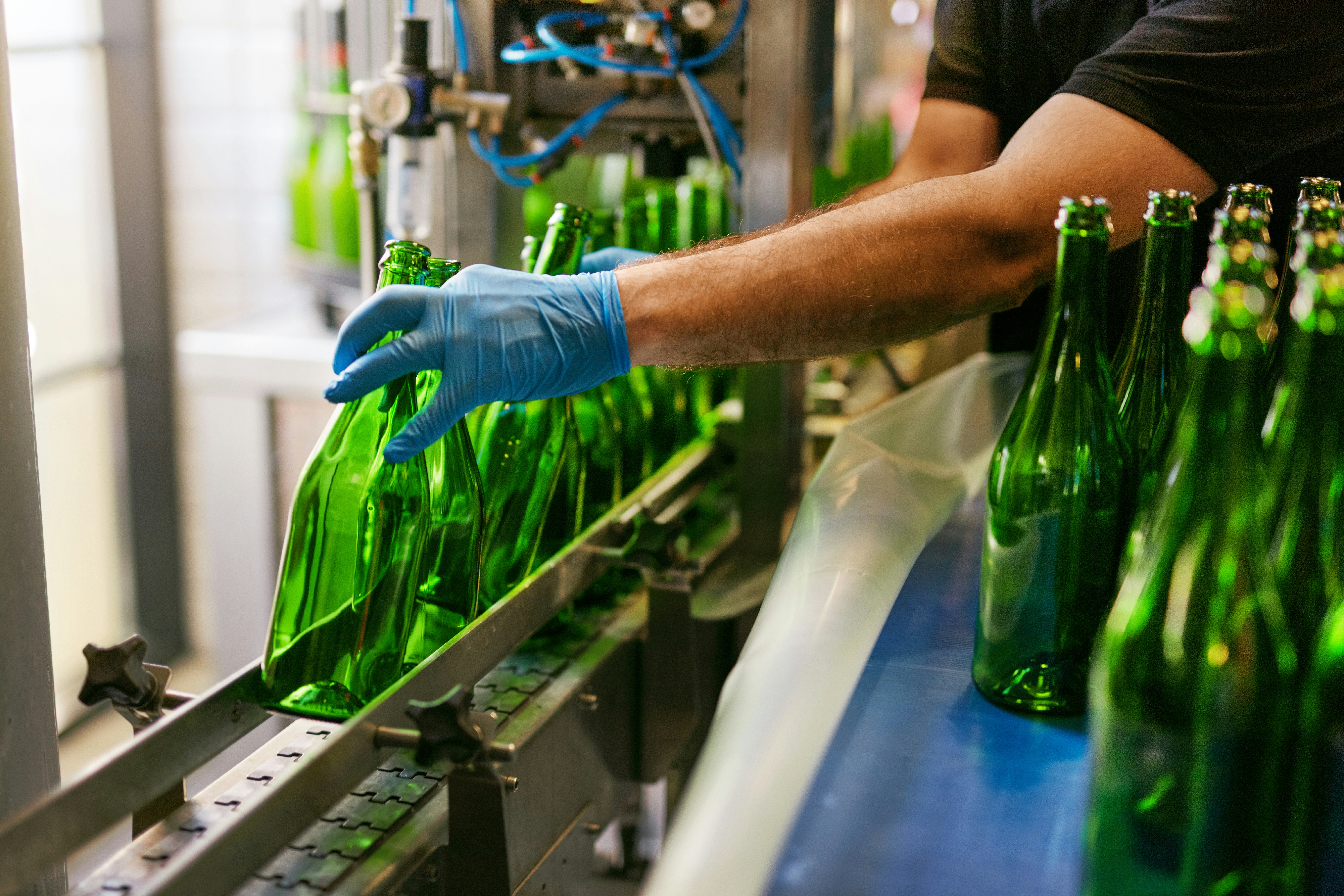 Un professionnel manipule des bouteilles sur une chaîne de production