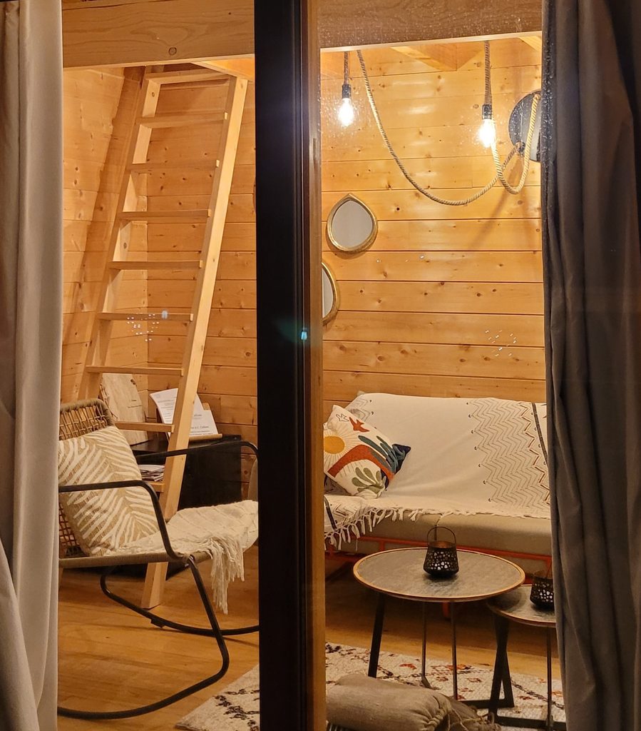 Coin salon en bois et escalier menant à la mezzanine de la cabane