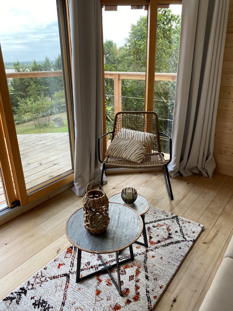 Fauteuil et table basse près des baies vitrées de la cabane