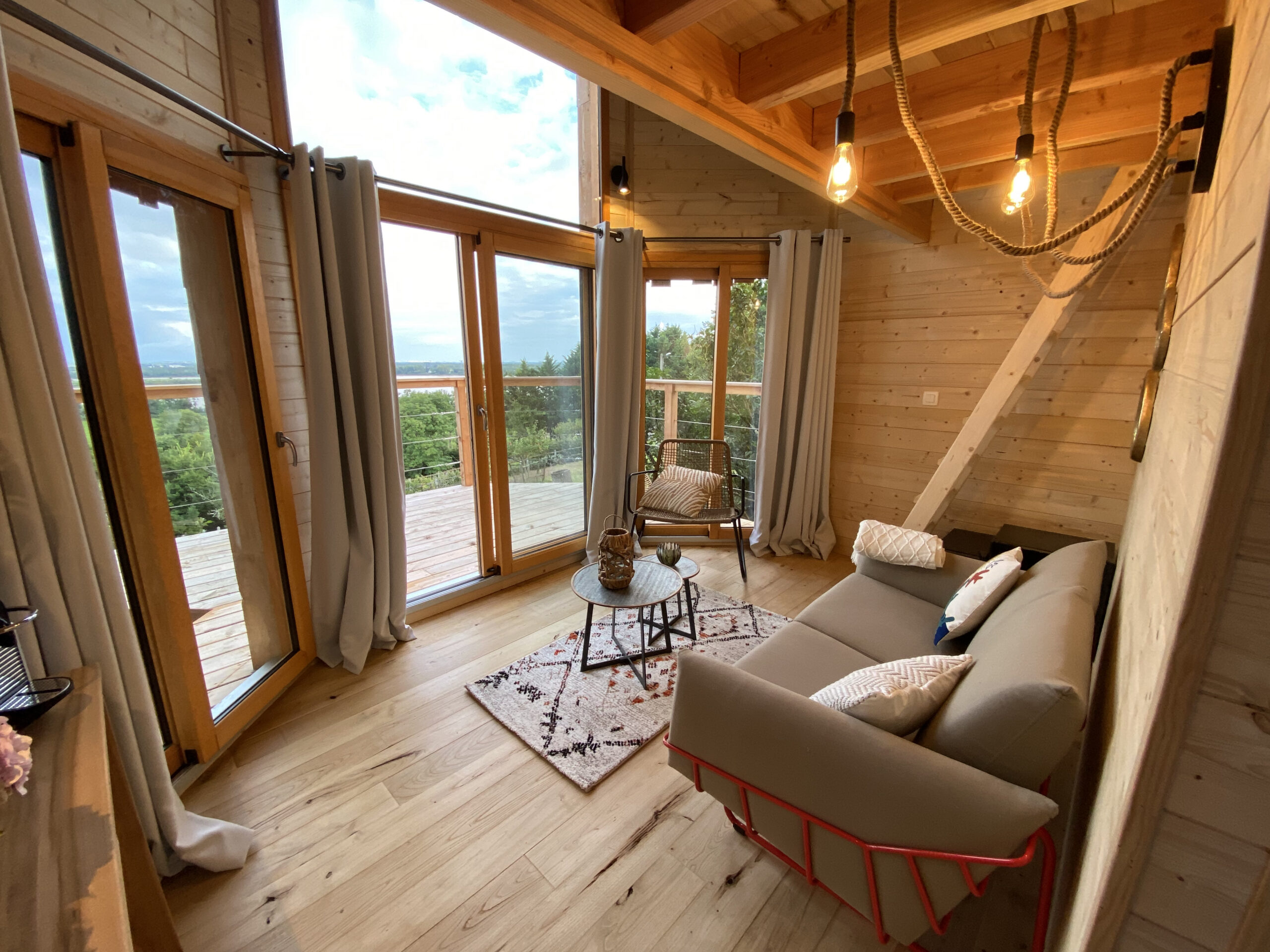 Pièce de vie en bois de C.Cabane avec larges baies ouvrant sur la terrasse