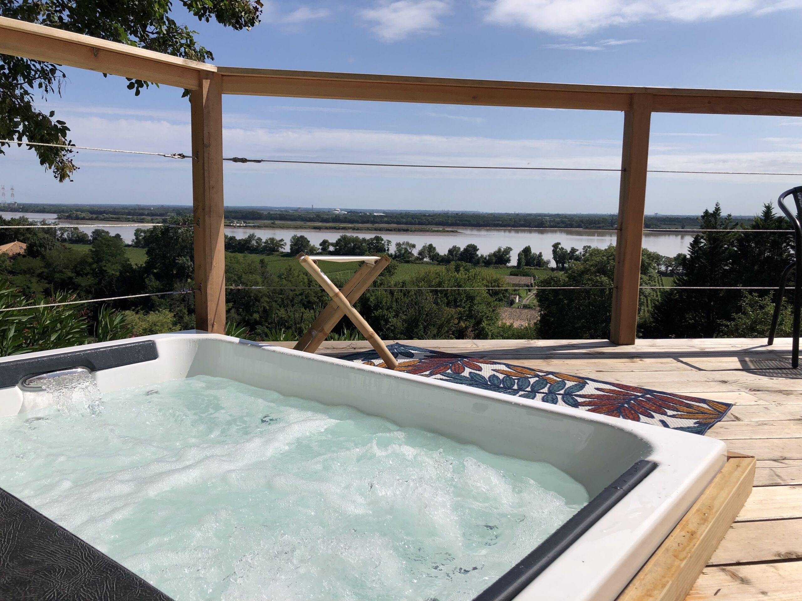 Spa privatif sur une terrasse en bois avec vue sur les vignes et la Gironde