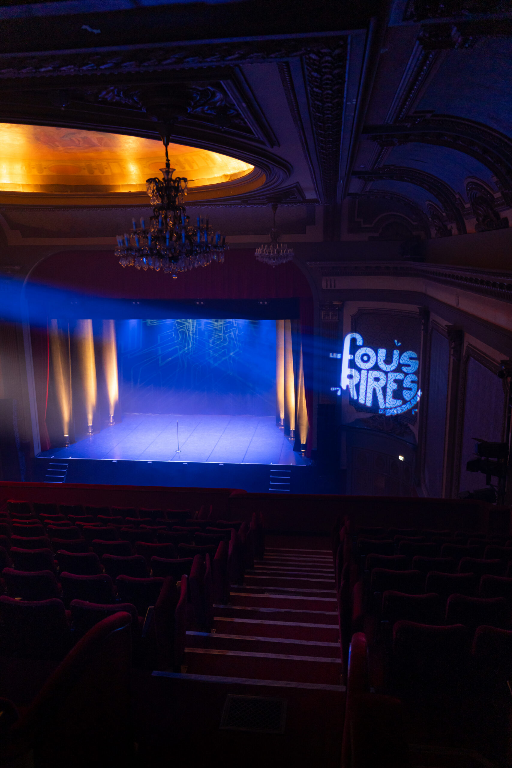 Scène de théâtre éclairée en bleu avec le logo des Fous Rires de Bordeaux