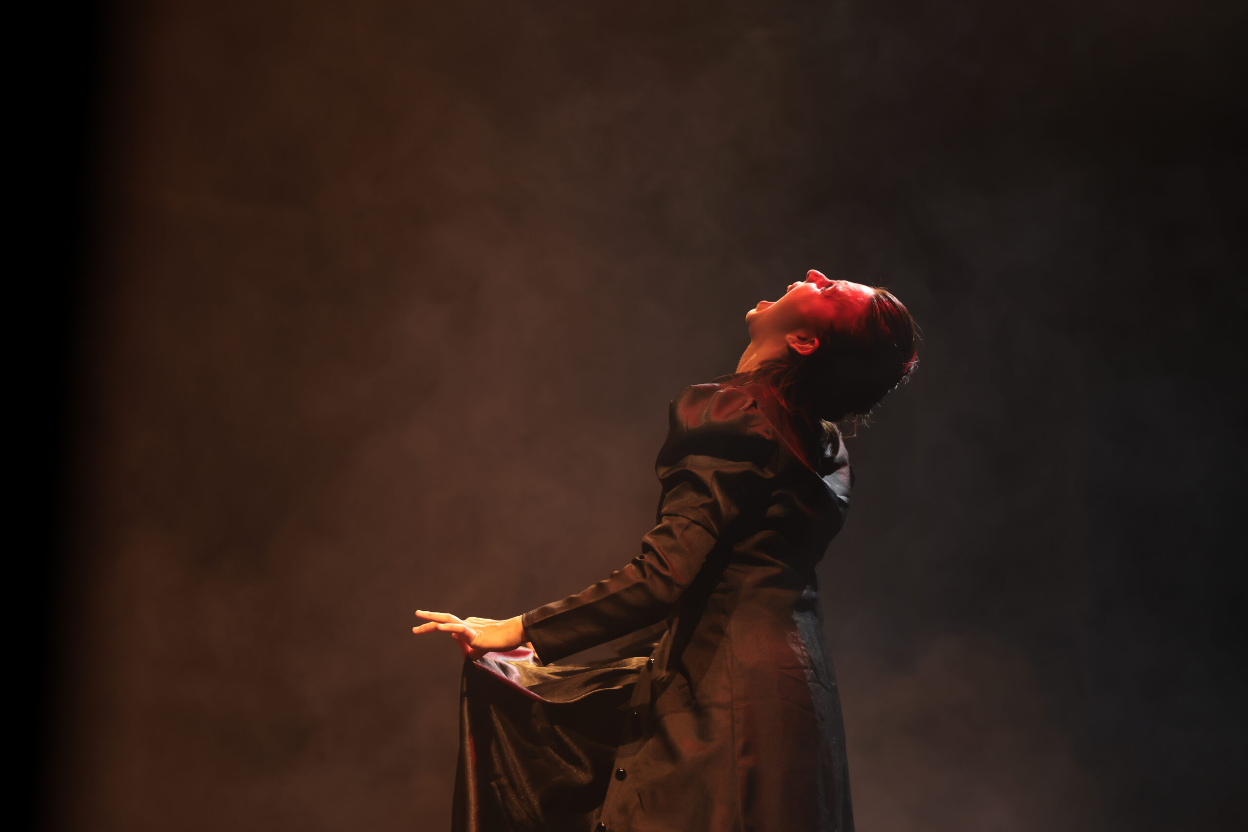 Artiste en costume noir dans une lumière théâtrale